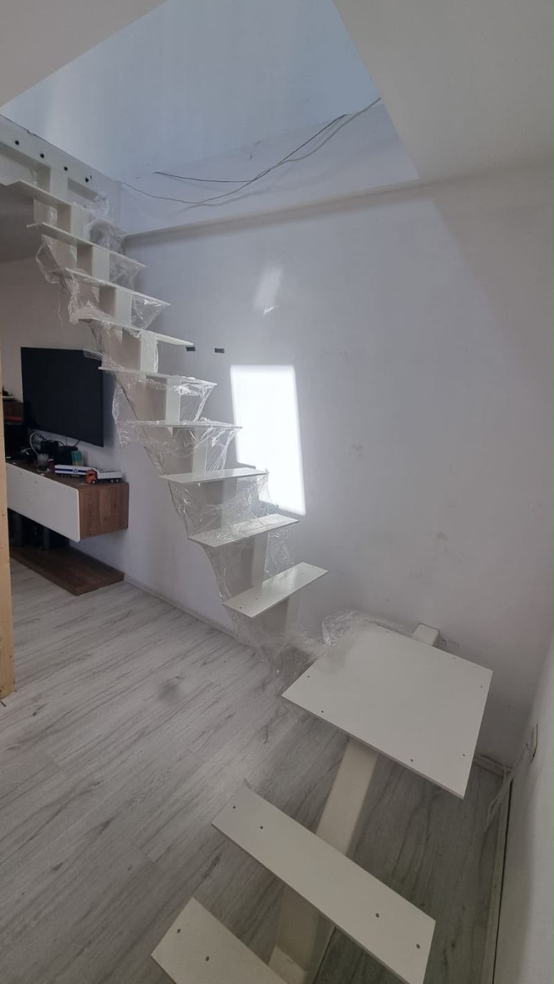 Scară interioară albă pe grindă centrală, cu trepte în consolă