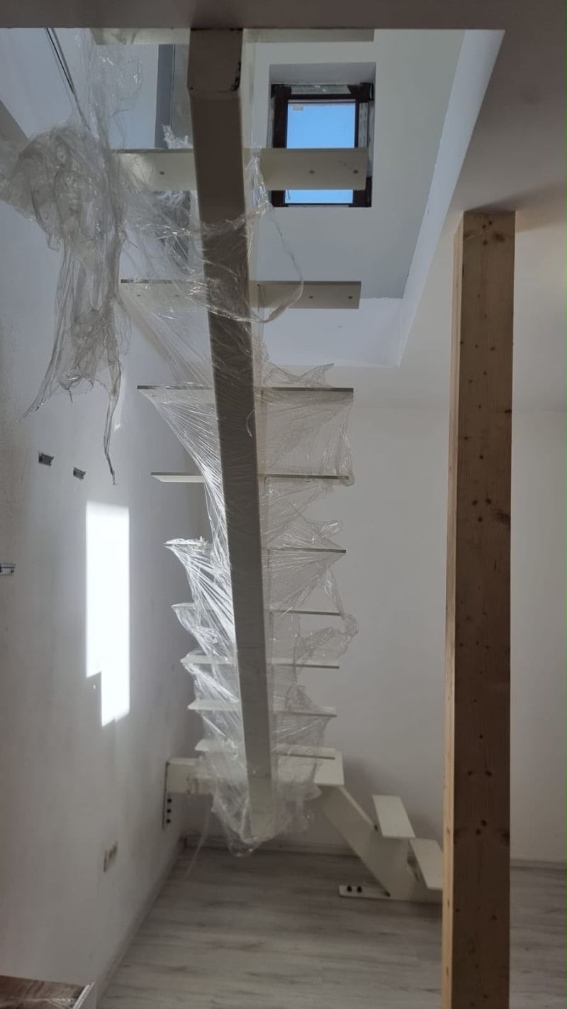 Scară interioară albă pe grindă centrală, cu trepte în consolă