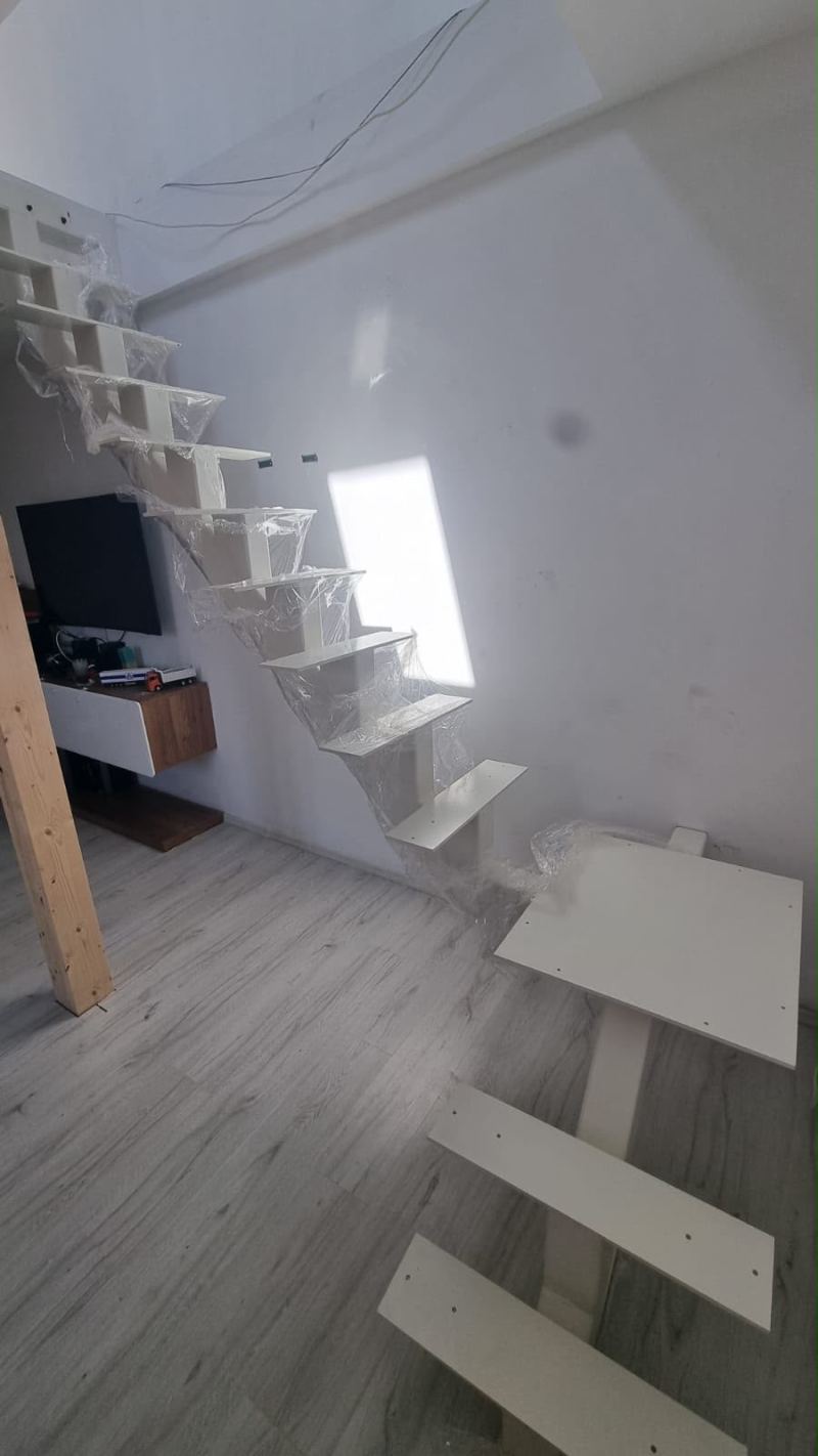 Scară interioară albă pe grindă centrală, cu trepte în consolă